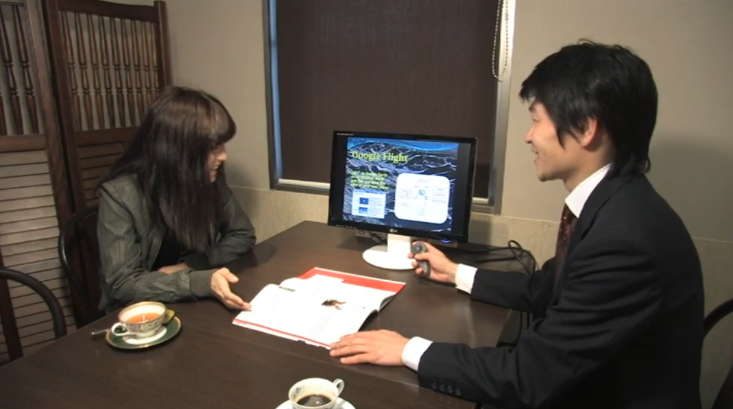 顧客と1対1の商談でテーブル上のモニターに映し出されたプレゼンをOZUpad AIRで操作している画像